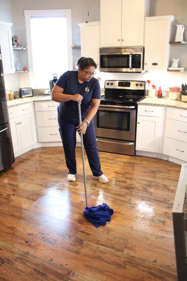A Leal&rsquo;s cleaner mopping a kitchen floor
