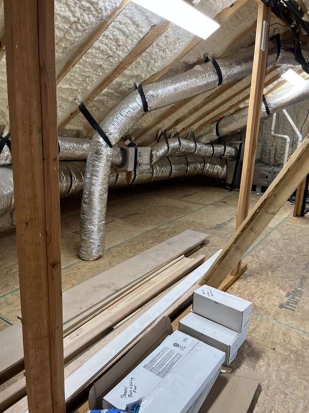 Attic with ductwork and framing before a post-construction clean